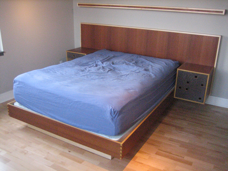 Custom-built bed with wall-hanging headboard and floating shelf.