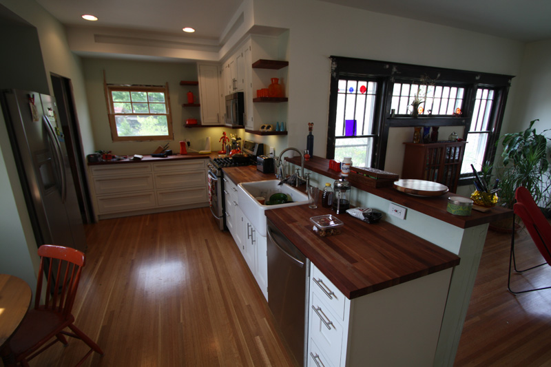 Kitchen cabinets with solid cherry butcher block countertops and floating shelves.