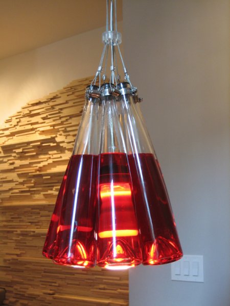 Light fixture built out of wine bottles filled with dyed fluid, wires, and other hardware.
